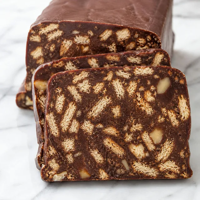 Sliced chocolate biscuit block with visible cookie chunks on a wooden board