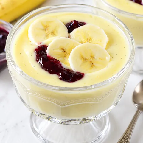 Budyń waniliowy z bananem i ciemnym dżemem w szklanym pucharku