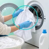 Osoba z białą koszulą przy pralce i jednym preparatem do wybielania tkanin.