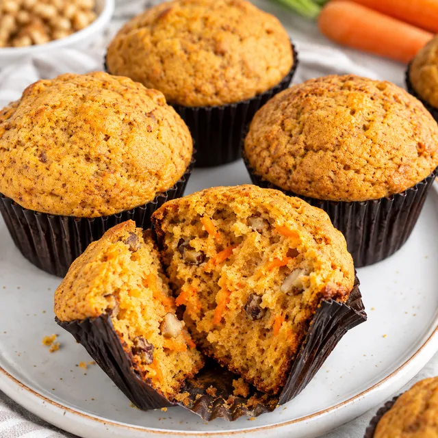 Muffinki marchewkowe z wilgotnym środkiem i orzechami na jasnym talerzu