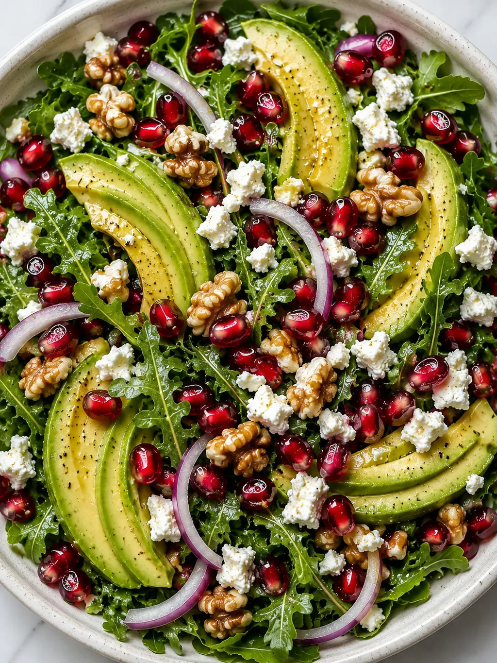 Top-down view of avocado and pomegranate salad with feta and walnuts